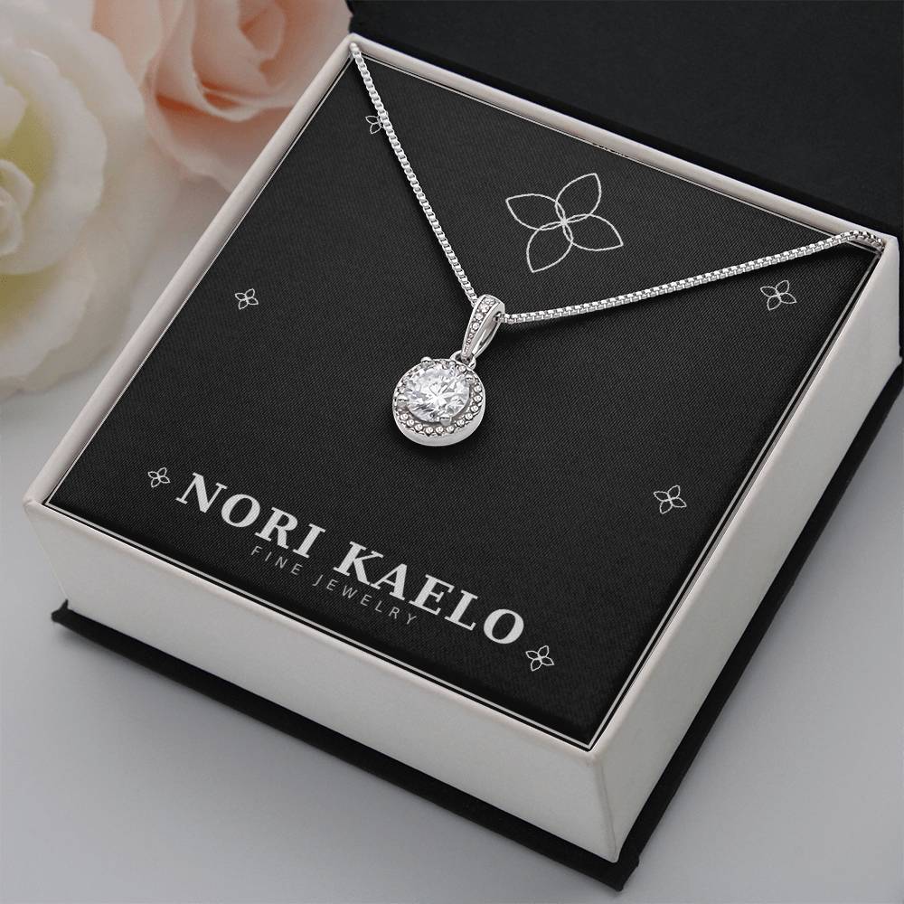 Halo pendant necklace displayed on a white gift box, styled with a pink rose in the background.