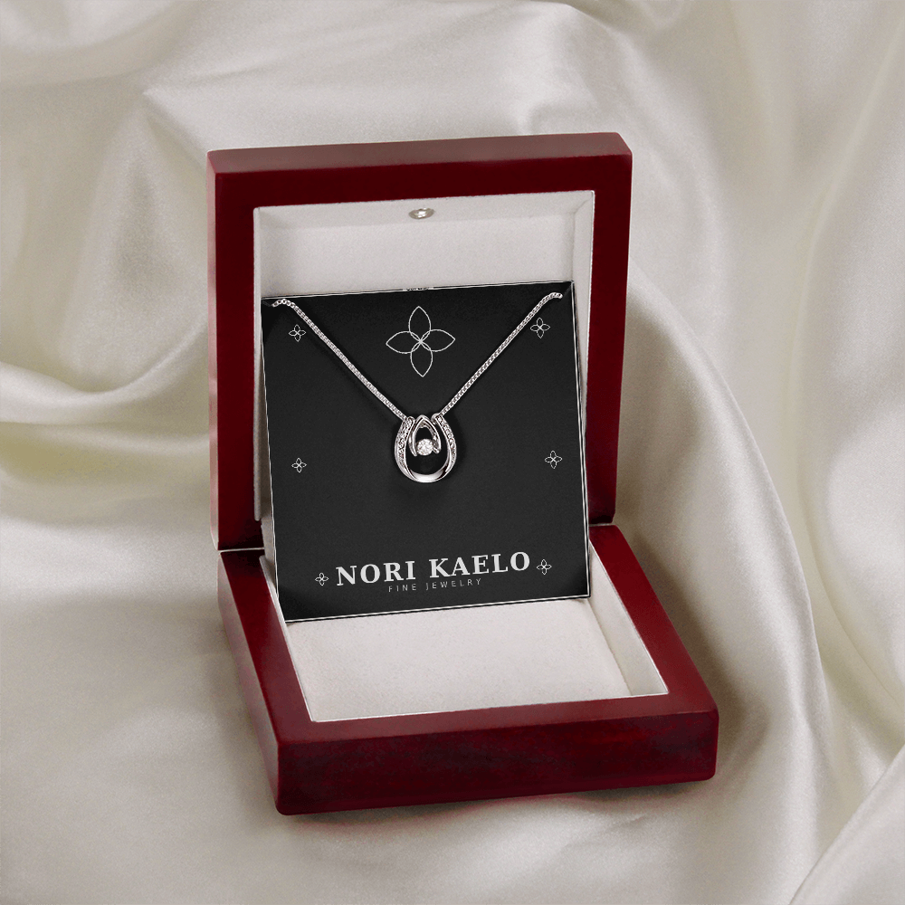 Dancing stone pendant necklace in white gold, displayed in a mahogany gift box on white satin fabric.