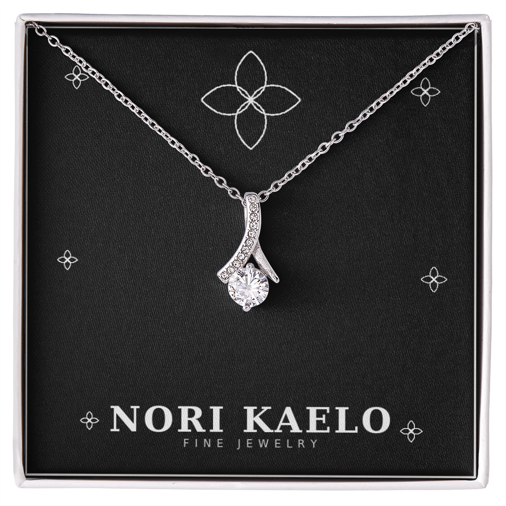 Ribbon pendant necklace in white gold, displayed on a black Nori Kaelo Fine Jewelry gift box.