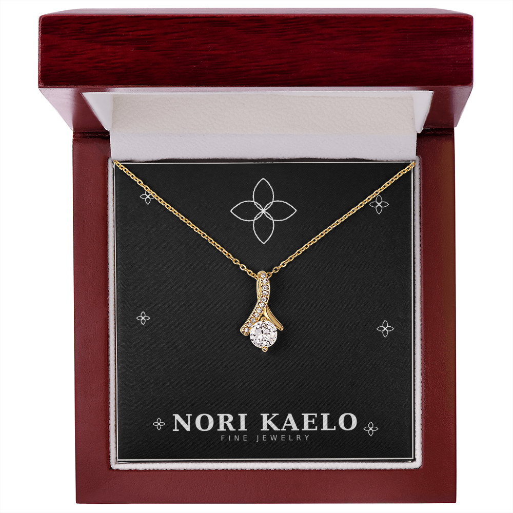 Ribbon pendant necklace in yellow gold, displayed in an open mahogany gift box.