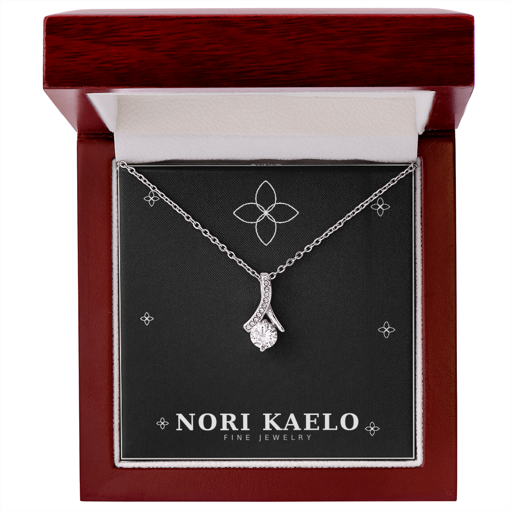 Ribbon pendant necklace in white gold, displayed in an open mahogany gift box.