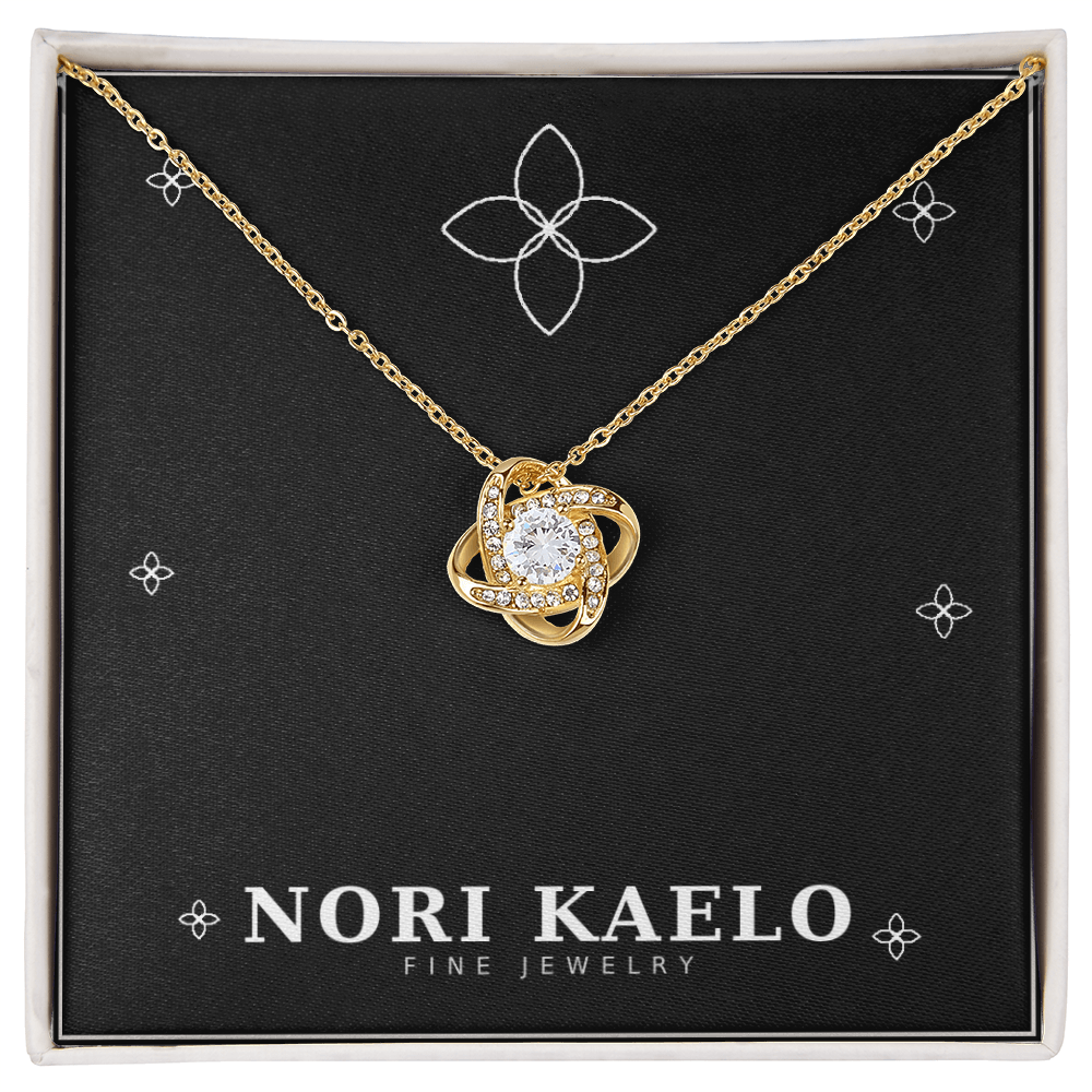 Love knot pendant necklace in yellow gold, displayed on a black Nori Kaelo Fine Jewelry gift box.
