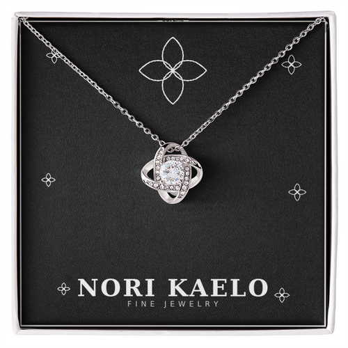 Love knot pendant necklace in white gold, displayed on a black Nori Kaelo Fine Jewelry gift box.