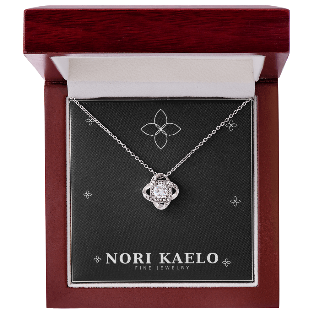 Love knot pendant necklace in white gold, displayed in an open mahogany gift box.
