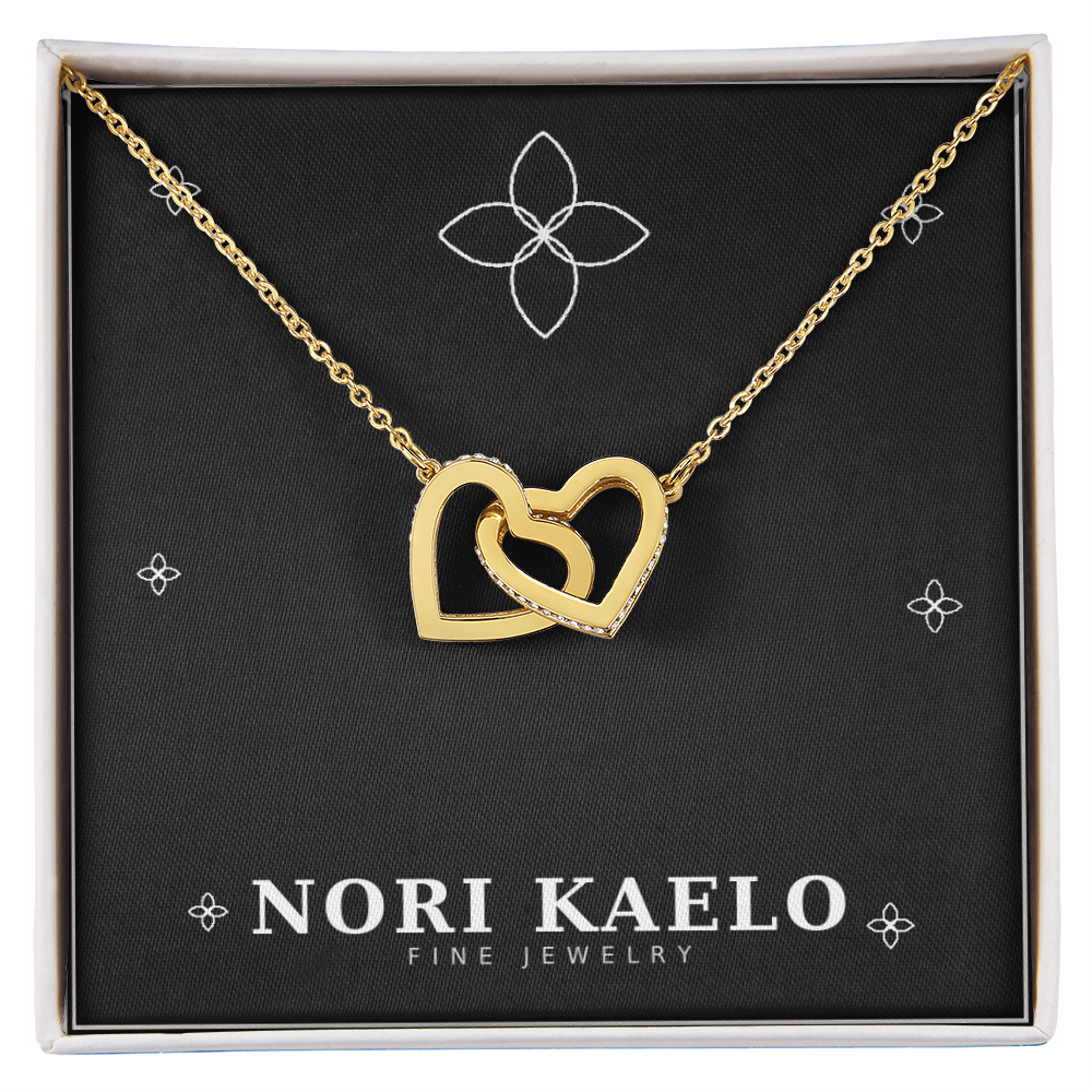 Interlocking hearts pendant necklace in yellow gold, displayed on a black Nori Kaelo Fine Jewelry gift box.