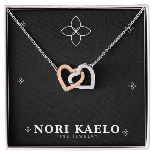 Interlocking hearts pendant necklace in rose gold and white gold, displayed on a black Nori Kaelo Fine Jewelry gift box.