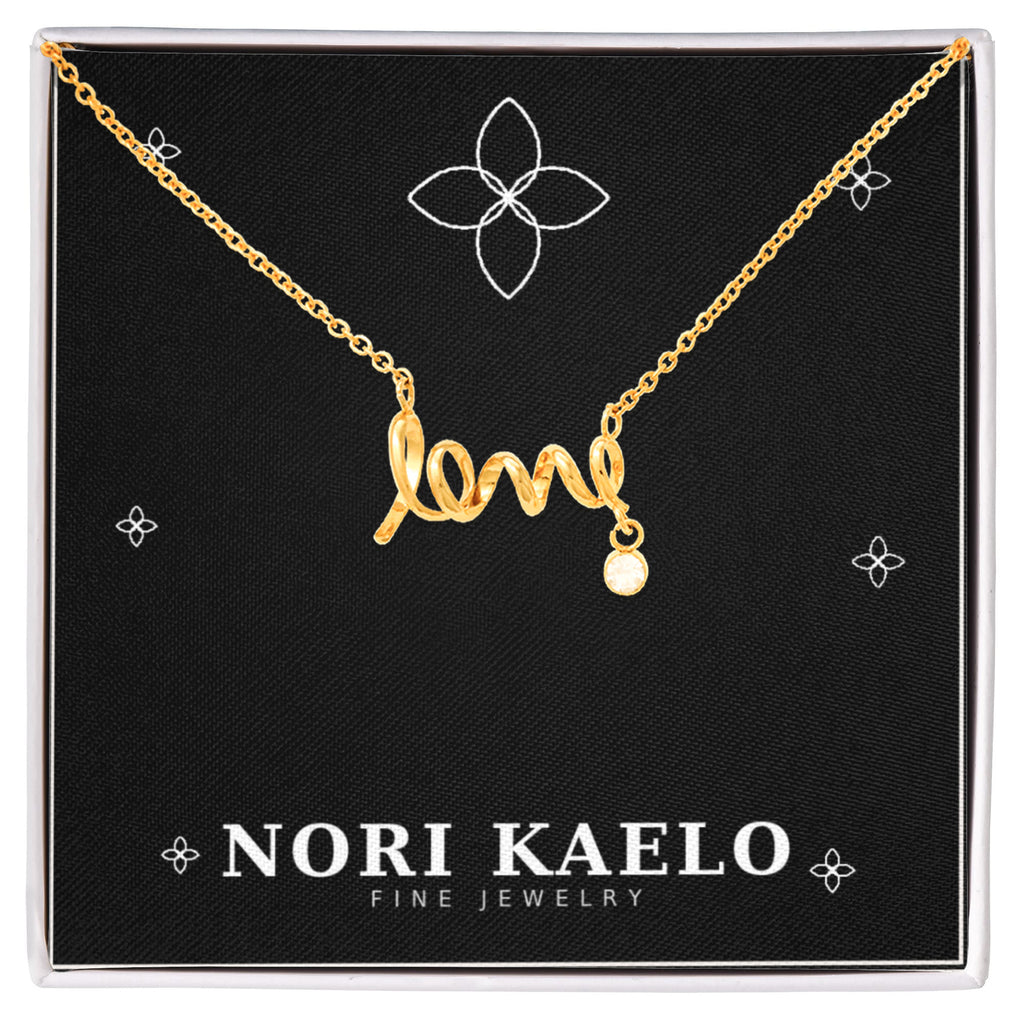 Cursive love pendant necklace in yellow gold finish, displayed on a black Nori Kaelo Fine Jewelry gift box.