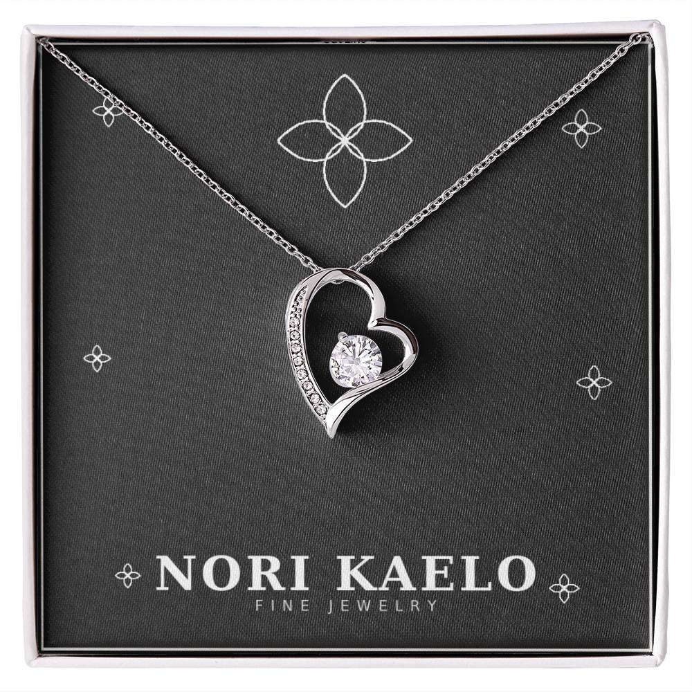 Open heart pendant necklace in white gold finish, displayed on a black Nori Kaelo Fine Jewelry gift box.